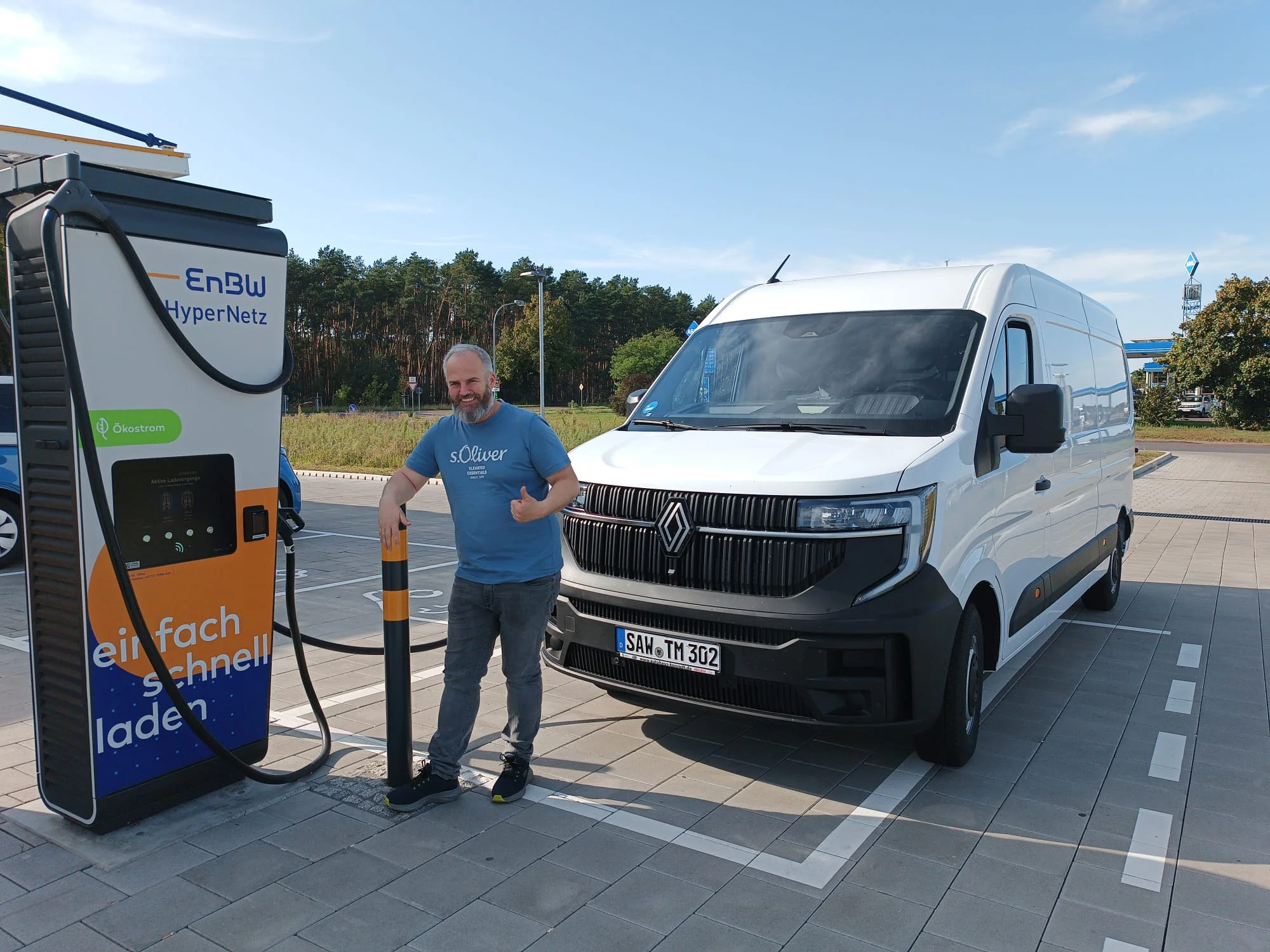 Elektrischer Transporter mit Mitarbeiter an einer Schnellladesäule